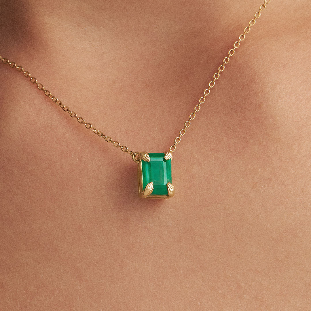 Modelo usando colar em ouro 18k de mãos e esmeralda retangular