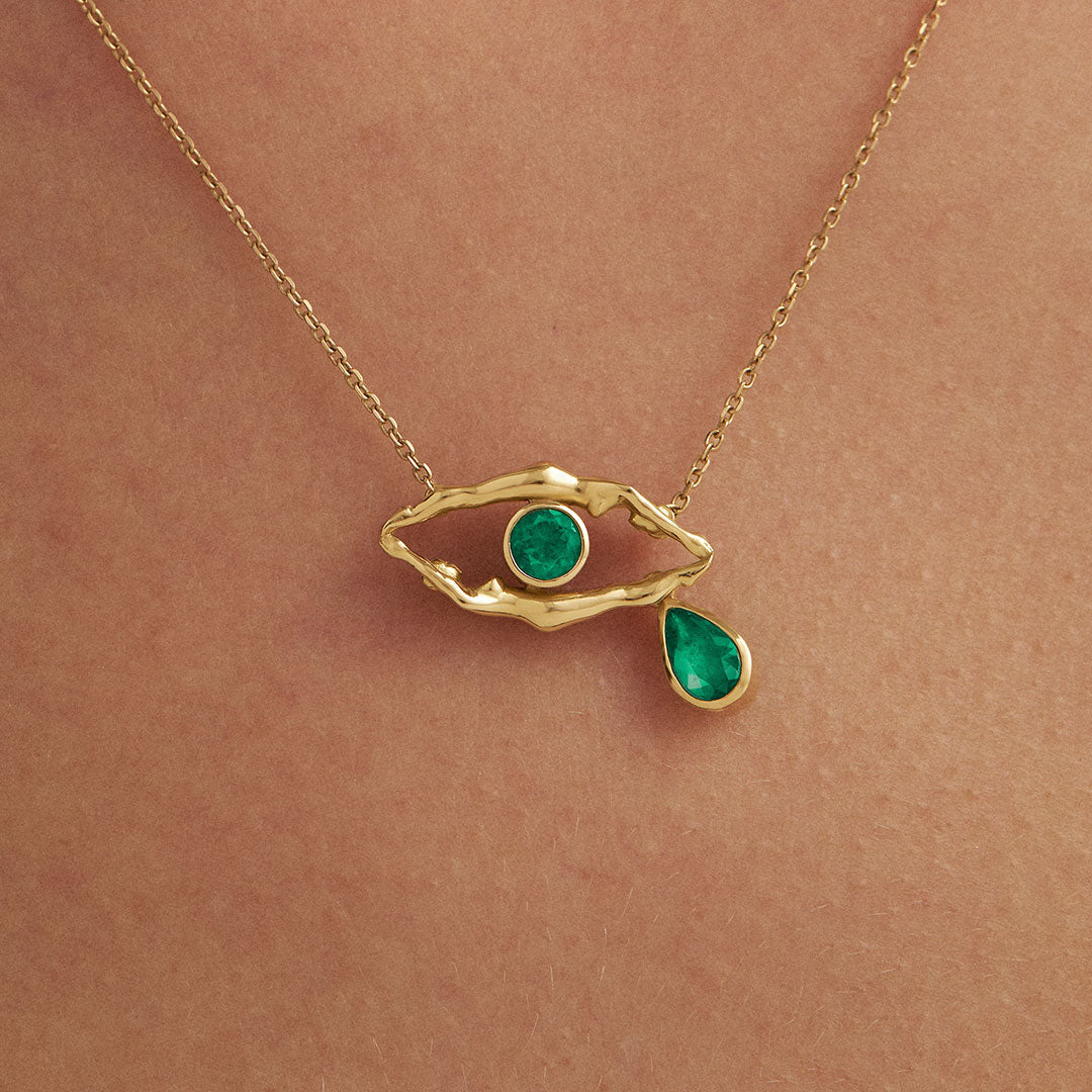 Modelo usando colar em ouro 18k de corpos femininos em formato de olho com esmeraldas